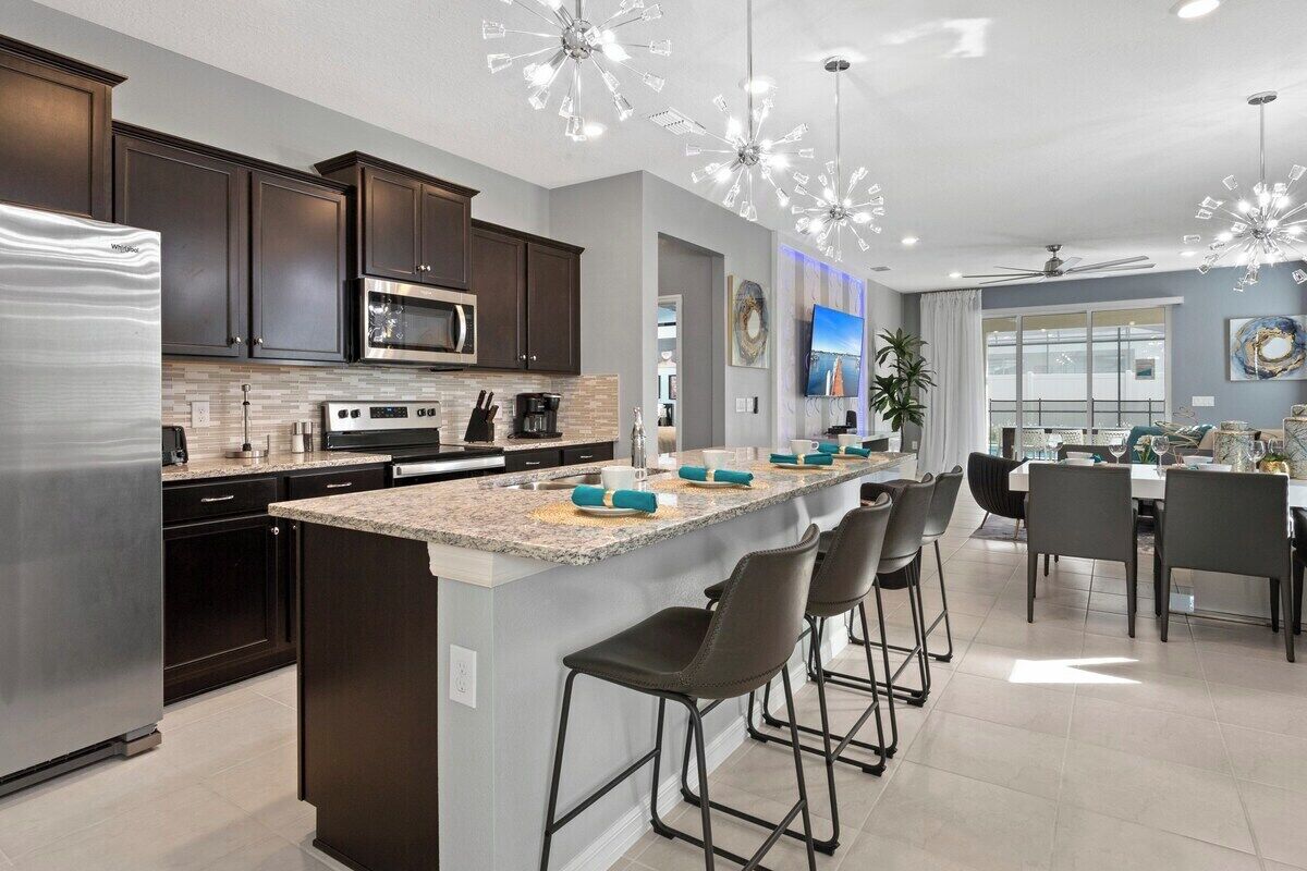 A modern kitchen with dark cabinets, stainless steel appliances, and a central island with bar stools.