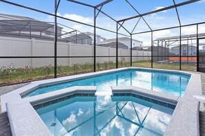 A swimming pool with a clear view of the surrounding area, including a fence and buildings in the background. - Ultimate Windsor Island 7BR Pool spa Game Room (Davenport)