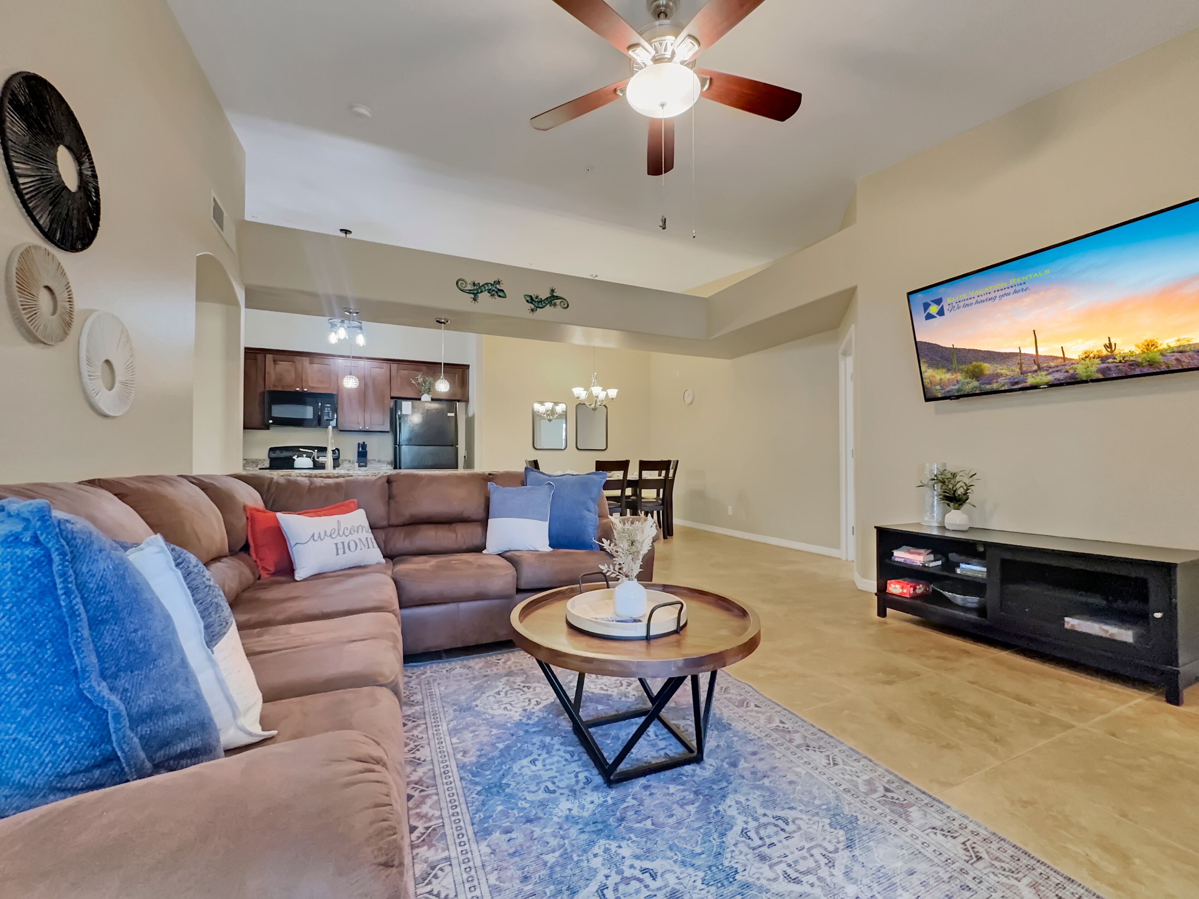A modern living room with a brown leather sofa, a round coffee table, and a flat-screen TV mounted on the wall.