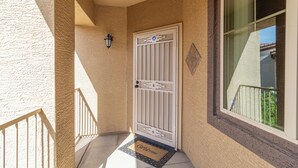A white door with a metal gate, a doormat with "Welcome" text, a small wall-mounted light, and a window with a view of greenery. - Southern #3116 Mesa (Mesa)
