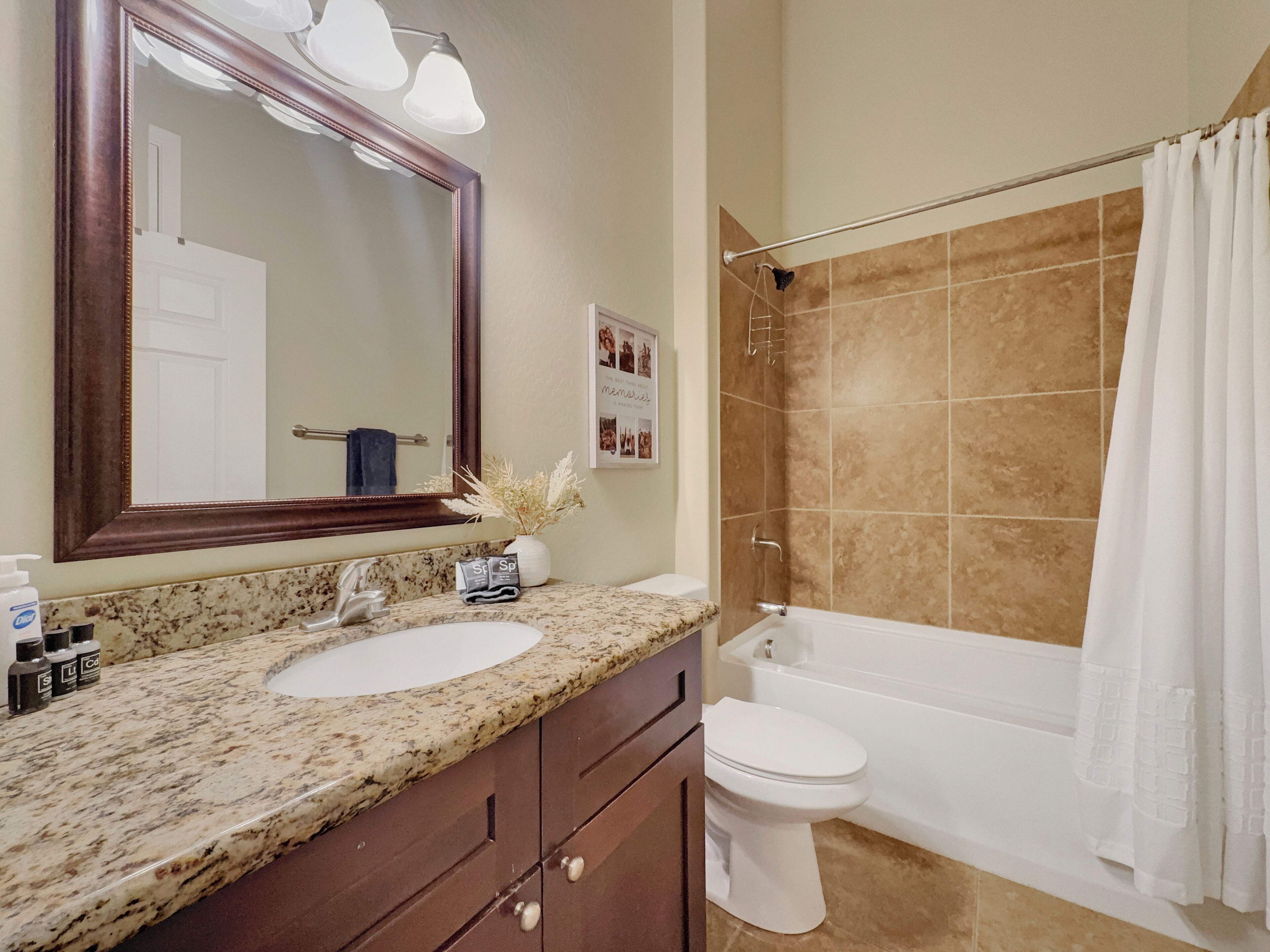 Une salle de bain avec un lavabo en marbre, des toilettes blanches, une baignoire et un rideau de douche.