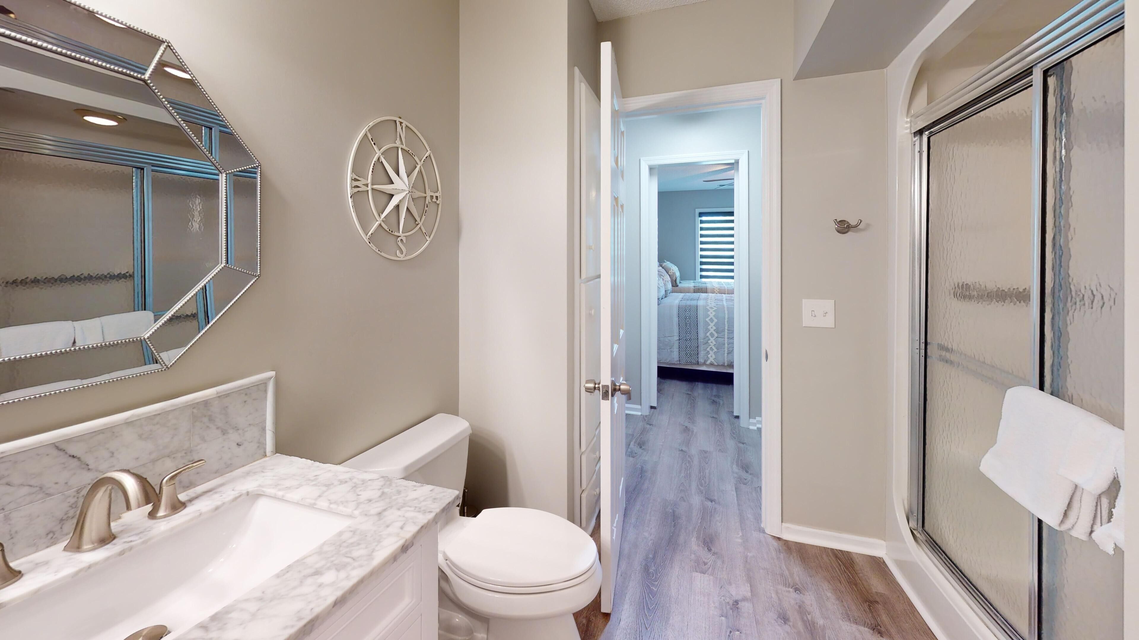 A bathroom with a marble sink, a toilet, and a shower with a glass door.
