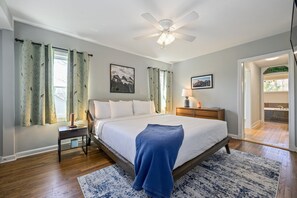 A bedroom with a bed, a nightstand, a lamp, a ceiling fan, and a view of the outside. - Plan A Trip To Georgia Aquarium In This Comfy 3BR (Hapeville)