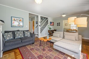 A living room with a gray sofa, a beige sofa, a patterned rug, and a staircase leading to another room. - Plan A Trip To Georgia Aquarium In This Comfy 3BR (Hapeville)