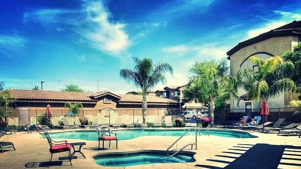 A pool area with lounge chairs, a small pool, and a building with a tiled roof. - Southern #2067 Mesa (Mesa)