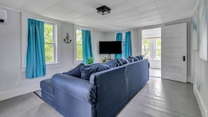 Una sala de estar moderna con un sofá modular, un televisor de pantalla plana y cortinas color turquesa.