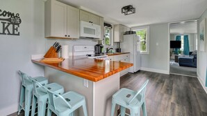 Una cocina moderna con armarios blancos, una isla de madera y taburetes de bar.