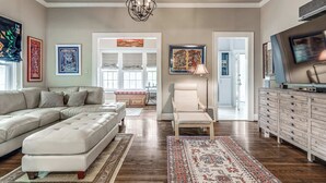 A spacious living room with a sectional sofa, a patterned rug, a wooden cabinet, and artwork on the walls. - Stylish 3-bedroom Home in Tulsa (Tulsa)