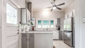 A modern kitchen with white cabinets, a central island, stainless steel appliances, and a ceiling fan. - Stylish 3-bedroom Home in Tulsa (Tulsa)