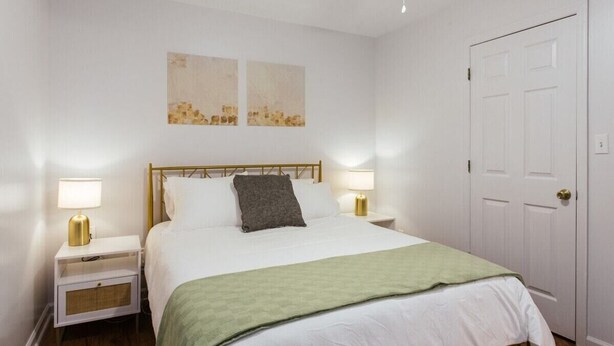A neatly arranged bedroom with a bed, two bedside tables, a nightstand, a door, and two wall-mounted artworks. - The Cozy Corner Near Downtown (Athens)