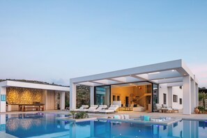 Ett modernt hus med en swimmingpool, en uteplats och en stenmur.