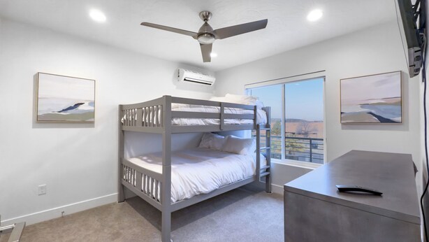 Habitación con literas, ventilador de techo, aire acondicionado y escritorio con control remoto.