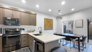 Una cocina moderna con electrodomésticos de acero inoxidable, una isla central y un comedor con vistas.