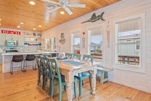 A wooden interior with a dining table, chairs, a kitchen area, and a ceiling fan. - Why Knot Relax - Heated Private Pool! Beach Gear Credit Included (Fresno)