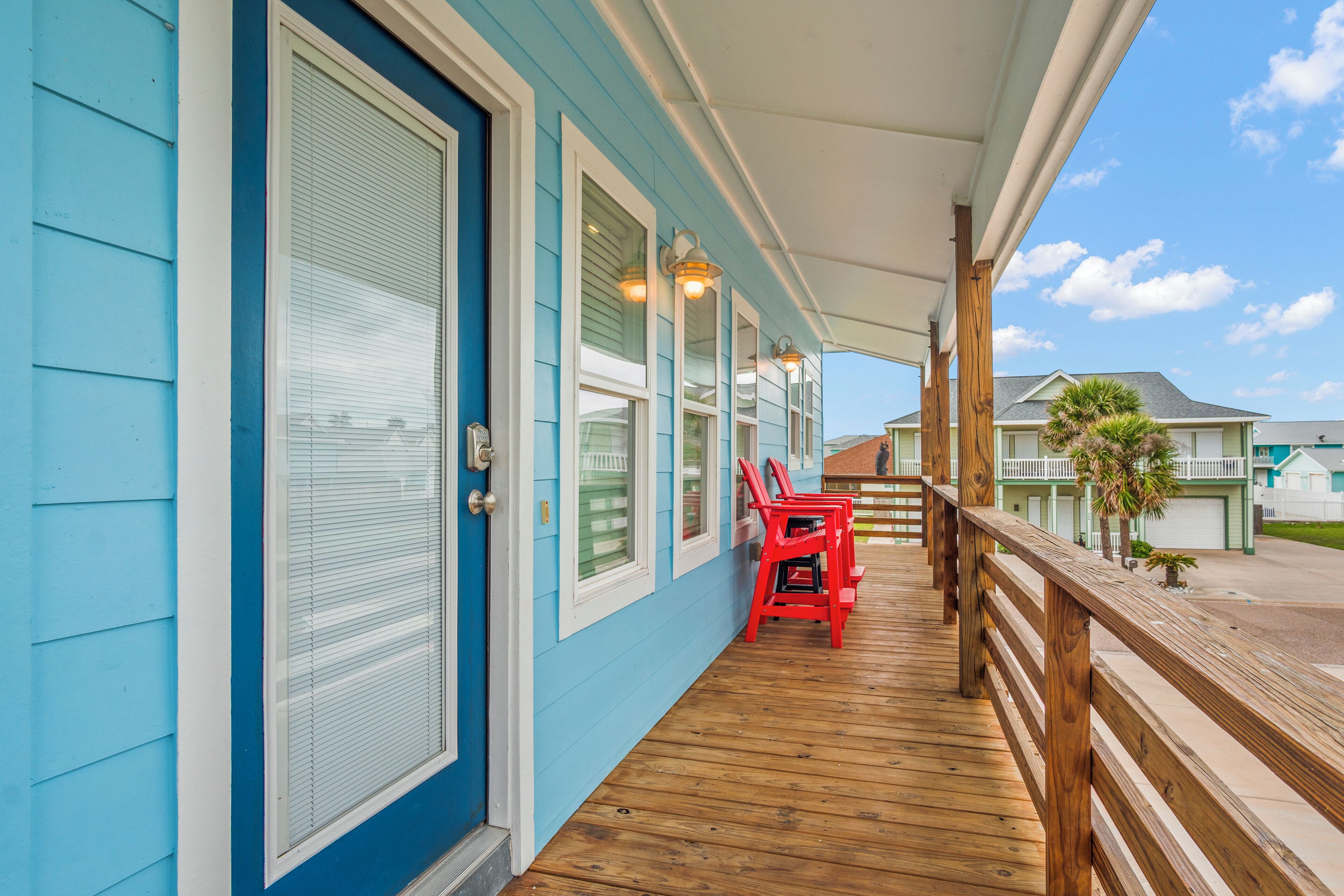 A covered porch with wooden railings and red chairs.