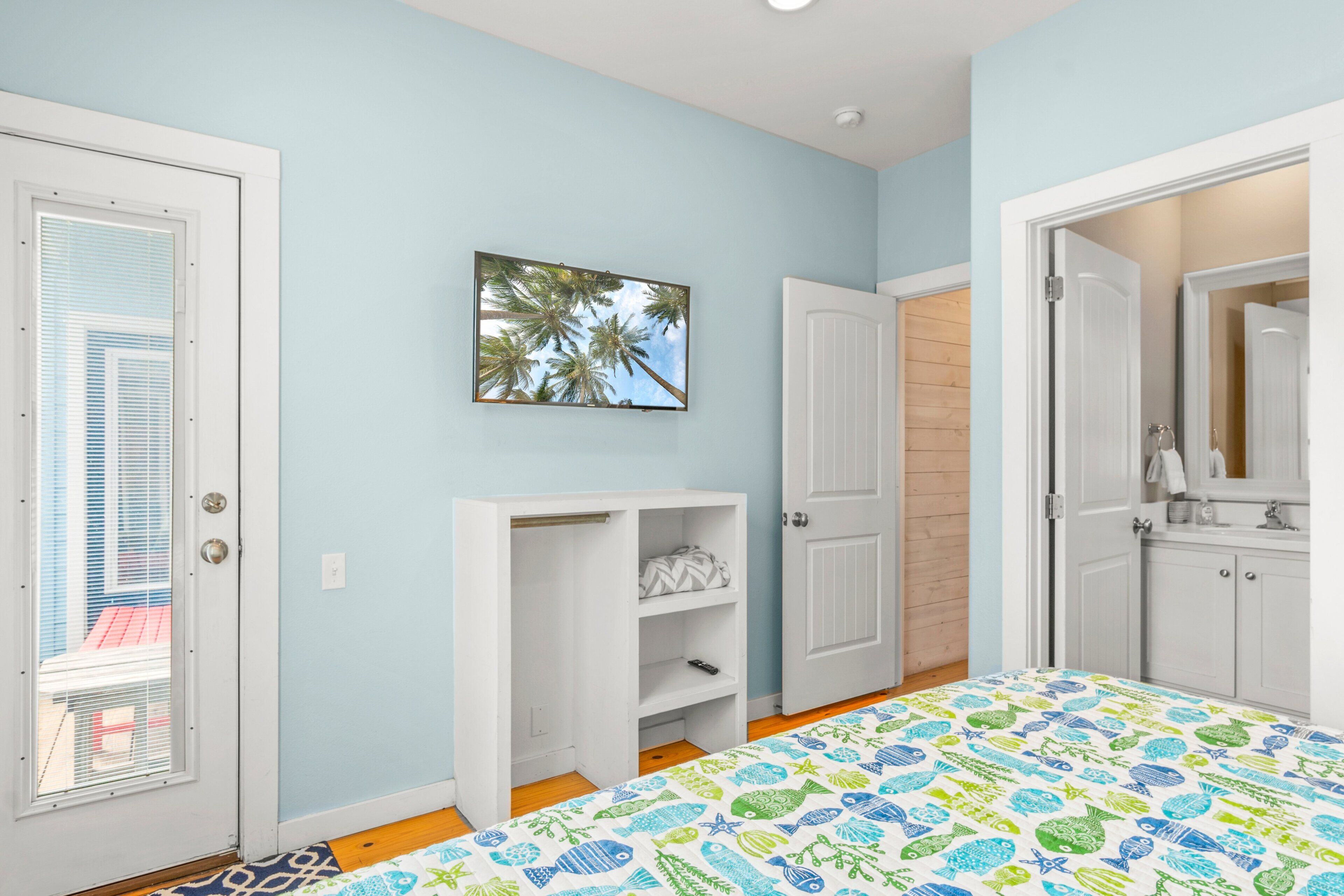 Un dormitorio con cama, un armario blanco, una estantería blanca, una puerta y una ventana con persianas.