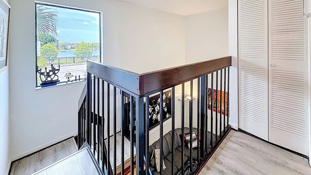 Apartamento moderno com escada de madeira, vista para a cidade e um armário branco.