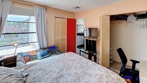 Quarto com cama, escrivaninha, televisão e armário.