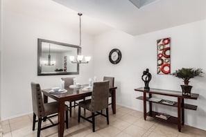 A dining area with a wooden table, four chairs, a chandelier, a wall clock, and a decorative piece. - Southern #1064 Mesa (Mesa)