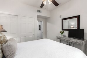 A bedroom with a bed, a TV on a console table, a ceiling fan, and a door leading to another room. - Southern #1064 Mesa (Mesa)