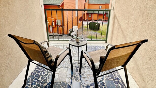 Un balcon doté d’un sol en mosaïque, de deux chaises et d’une petite table.