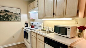 Une cuisine avec des meubles de rangement en bois, un four à micro-ondes, une cuisinière et un lave-vaisselle.