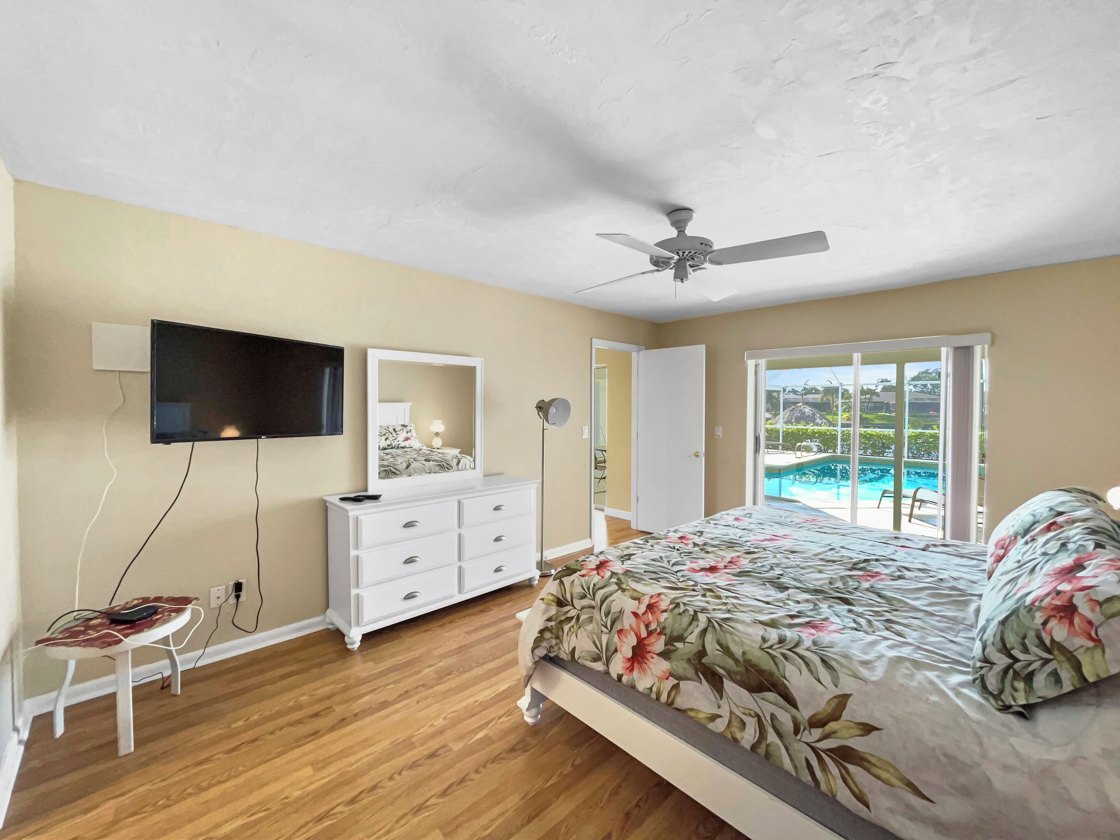 Une chambre à coucher comprenant un lit, une télévision, une commode et un ventilateur de plafond.