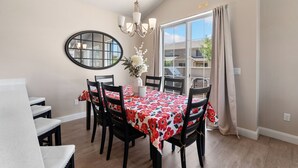 A dining area with a table set for six, a chandelier, a mirror, and a view of the outside. - Casita Respite (Washington)