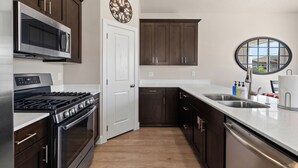 A modern kitchen with dark wood cabinets, stainless steel appliances, and a white countertop. - Casita Respite (Washington)