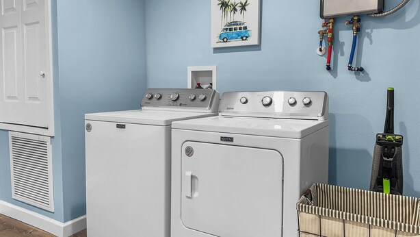 A laundry area with two Maytag washers and dryers, a vented dryer, a water heater, and a laundry basket labeled "LAUNDRY." - Blue Haven A (Sarasota)