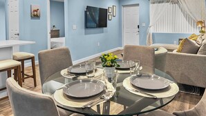 A modern dining area with a glass table set for four, surrounded by comfortable seating. - Blue Haven A (Sarasota)