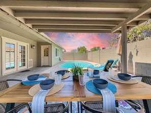 Eine Terrassenanlage im Freien mit Pool, Esstisch gedeckt mit Schüsseln und Gläsern sowie Lounge-Stühlen.