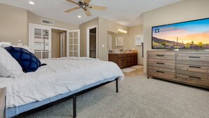A bedroom with a bed, a ceiling fan, a dresser, a vanity, and a TV displaying a desert landscape. - Yorkshire Glendale (Glendale)