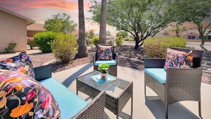 An outdoor seating area with wicker furniture and colorful cushions, surrounded by landscaping and trees. - Yorkshire Glendale (Glendale)
