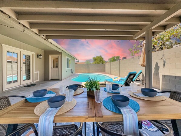 An outdoor dining area with a pool, covered patio, and a view of the backyard. - Yorkshire Glendale (Glendale)