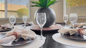 A dining table set with plates, napkins, and wine glasses, centered around a potted plant. - Yorkshire Glendale (Glendale)