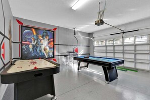 Una mesa de billar, una pantalla de proyector con una película temática del espacio y una puerta de garaje.