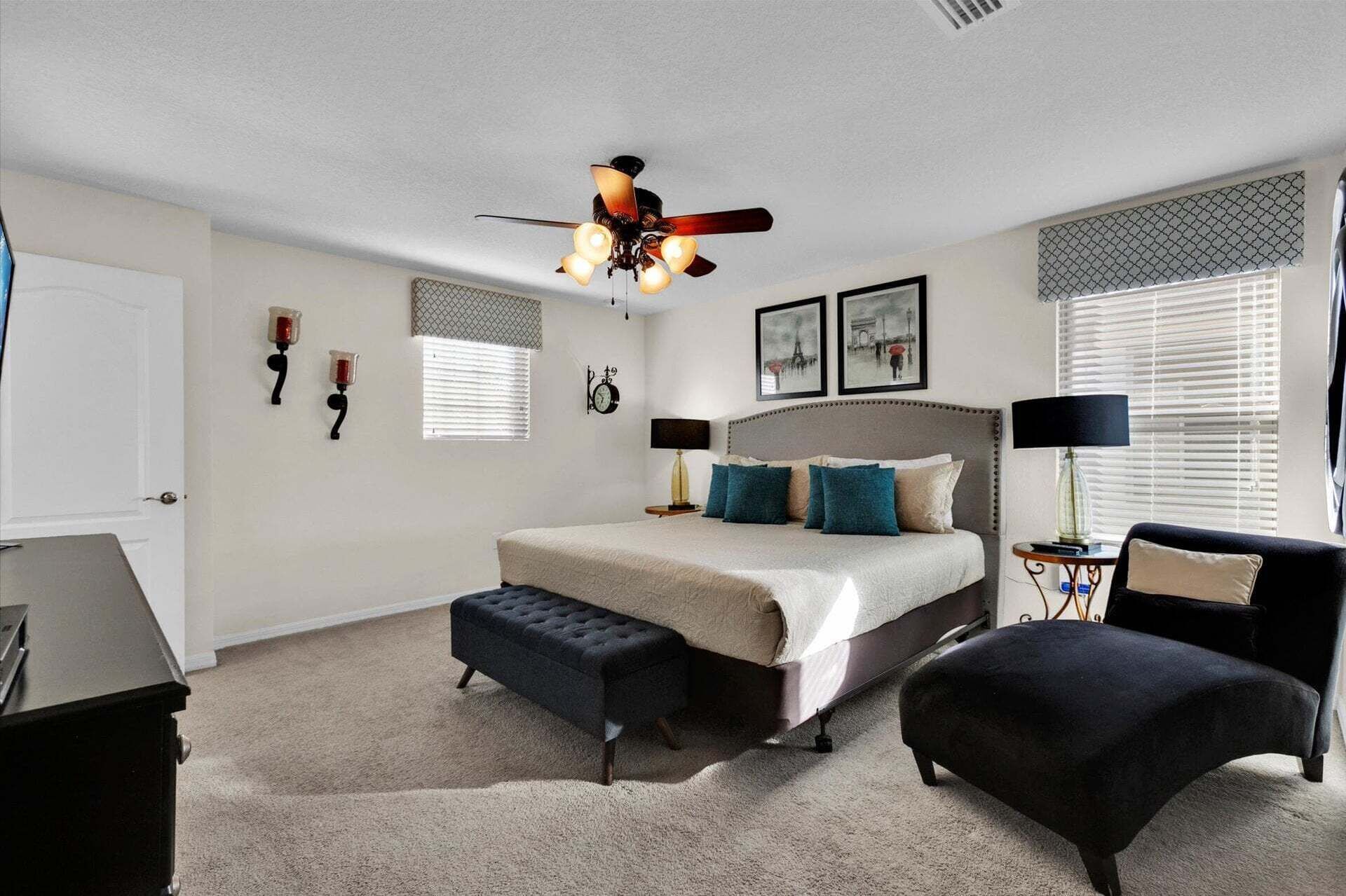 A bedroom with a bed, a bench, a chair, a ceiling fan, and a window with blinds.