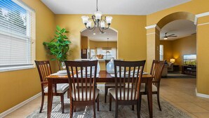 A dining area with a chandelier, a potted plant, and a view into the kitchen. - Windsor Hills Resort Vacation Home Ts7718 (Kissimmee)