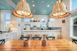 A kitchen with wooden ceiling, white cabinets, and a central island with stools. - Mermaid Retreat - Ocean Views! Golf Cart Included! (Port Aransas)