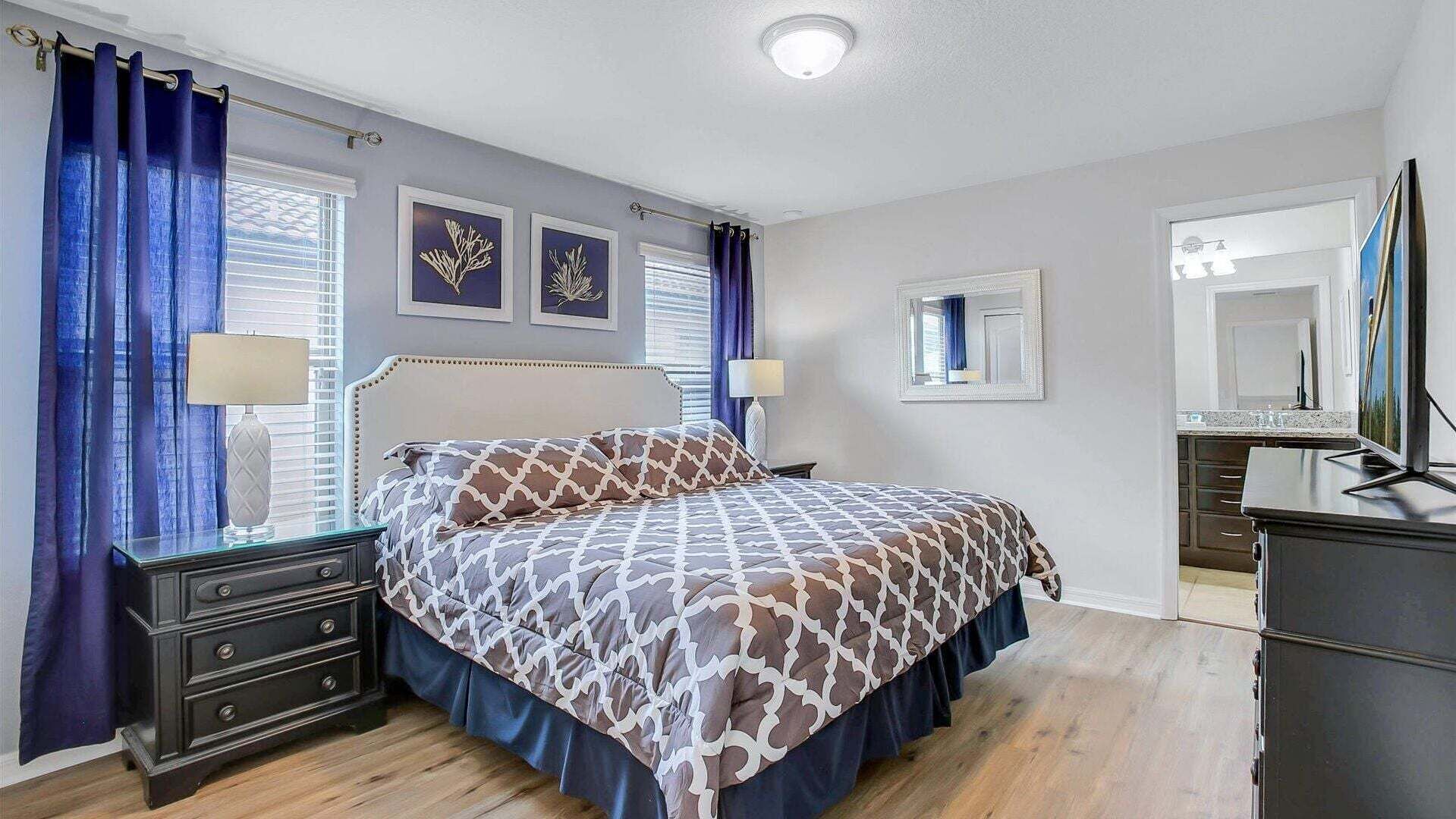 A bedroom with a bed, nightstands, a dresser, a mirror, and artwork on the walls.