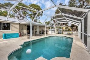 Une piscine couverte avec un jacuzzi intégré, des chaises longues et un espace barbecue.
