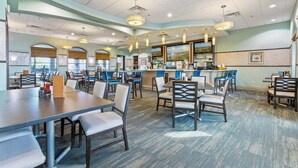 A restaurant with multiple dining tables and chairs, a bar area, and a view of the outdoors. - Mvd1562 (Davenport)
