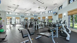 A gym with various exercise machines, a bench press, and a television screen. - Mvd1562 (Davenport)