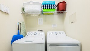 Two white front-loading washing machines, a laundry basket, and a shelf with folded towels. - Mvp9018sdcg (Davenport)