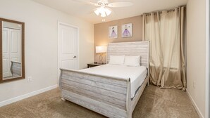 A bedroom with a wooden bed, a ceiling fan, a nightstand, a lamp, and a door. - Mvp9018sdcg (Davenport)
