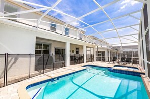 Ein Poolbereich mit Glasveranda, Liegestühlen und einer überdachten Terrasse.