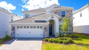 A two-story house with a stone facade, a tiled roof, and a front garage. - Mvp9018sdcg (Davenport)