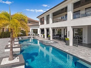 A modern two-story building with a swimming pool, outdoor seating, and a patio area. - Nm501l Legends Palazzo (Kissimmee)