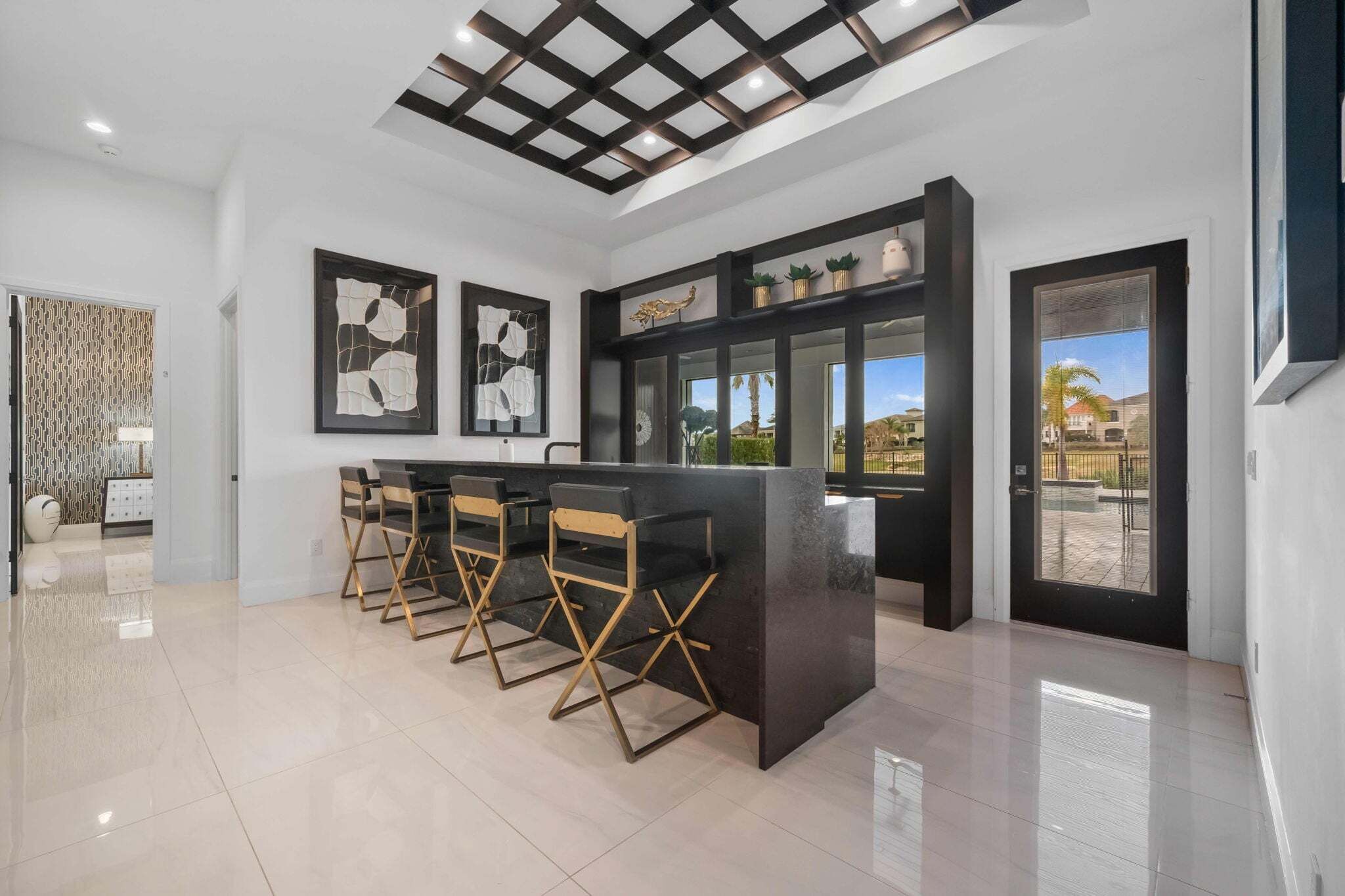 A modern kitchen with a bar area, a dining set, and a view of the outdoors.
